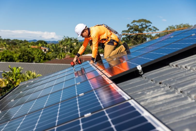 technician on roof installing solar panels