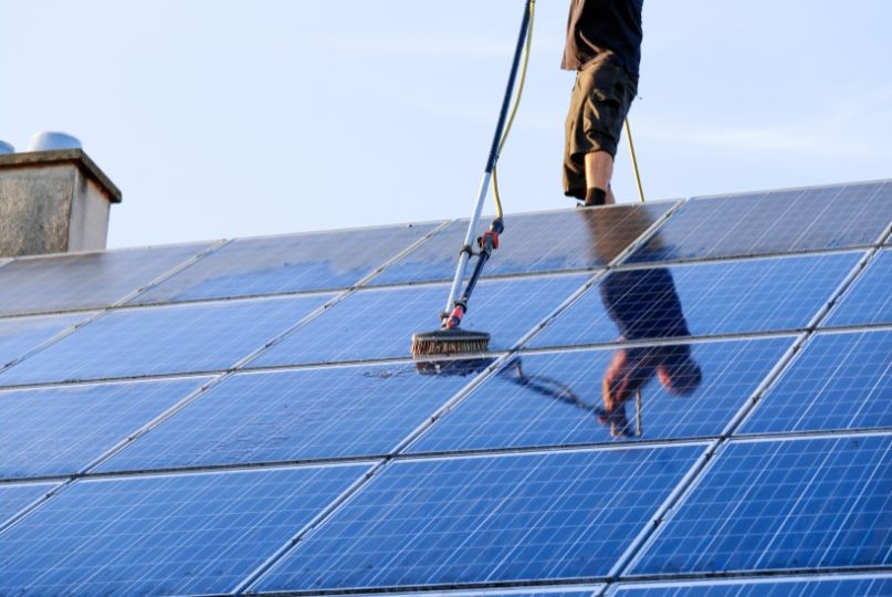 man on roof cleaning solar panels